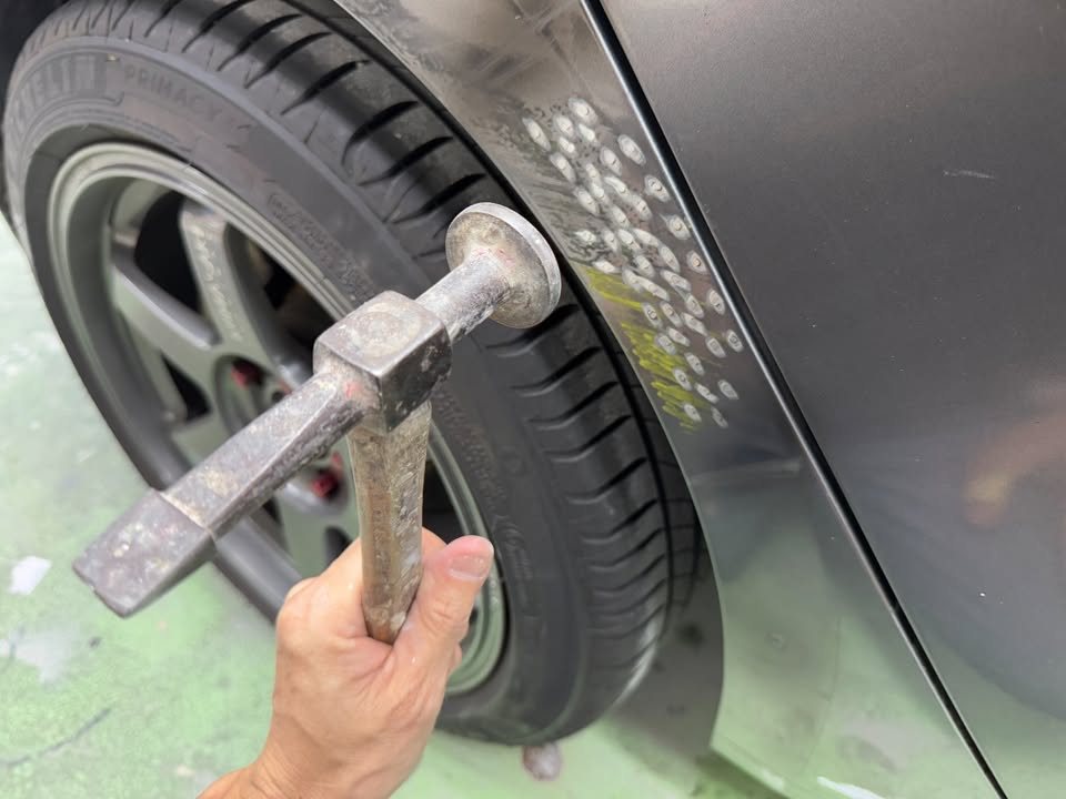 Slide hammer pulling a dent near the rear wheel arch.
