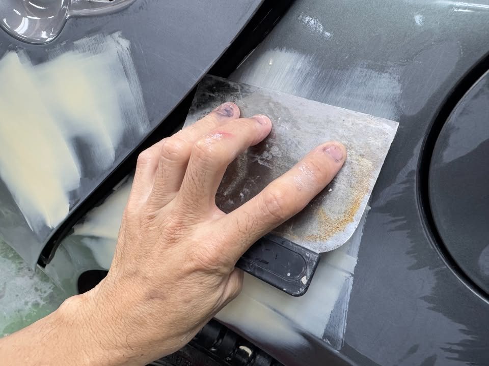 Filler being spread on the rear quarter panel.