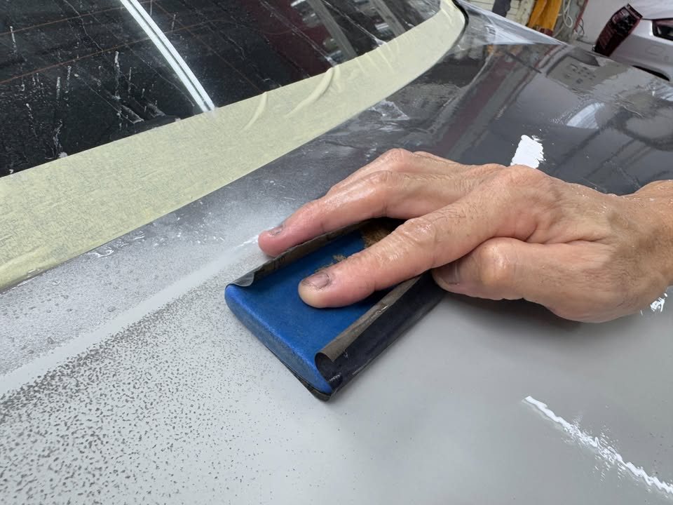 Blue sanding block on a primed panel.