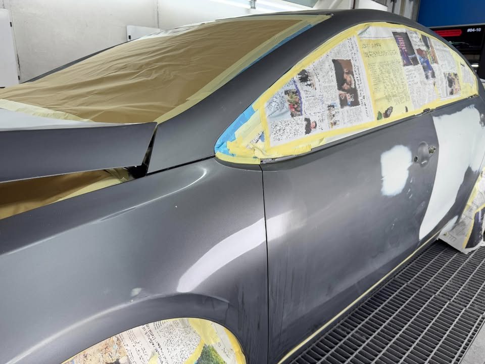 Car masked with newspaper and tape over the windows in the booth.