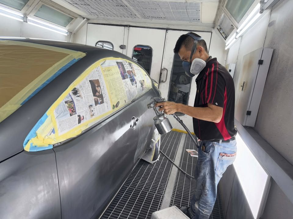 Painter spraying the masked grey Forte inside the spray booth.