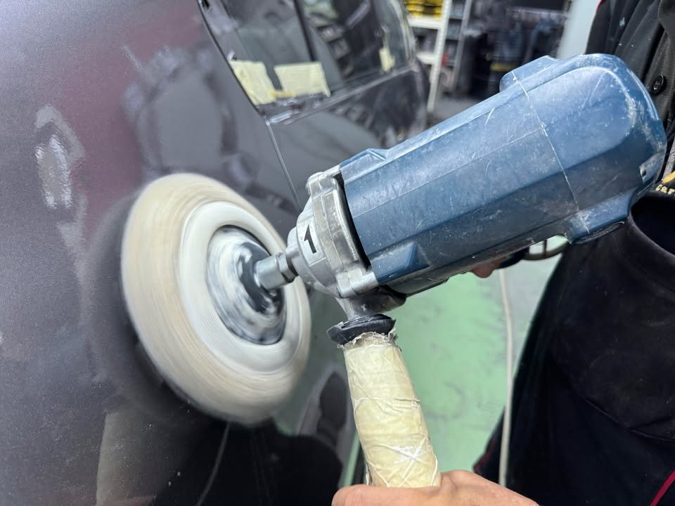 Rotary polisher working the freshly painted grey panel.