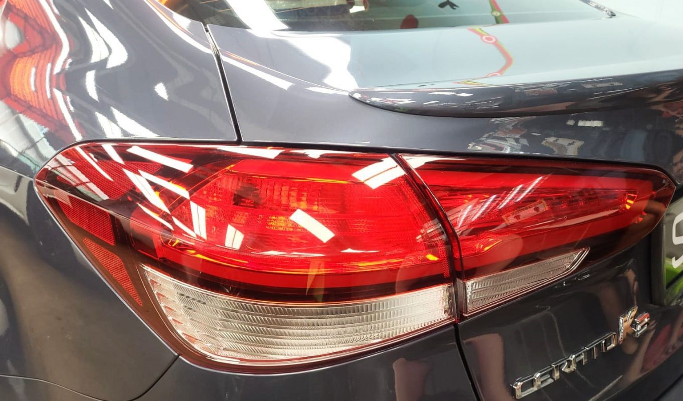 Bonnet of the Kia Forte K3 under workshop lighting.
