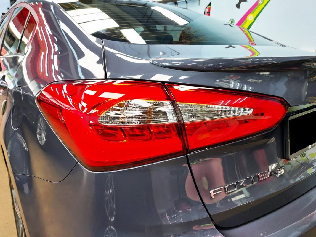 Bonnet of the Kia Forte K3 under workshop lighting.