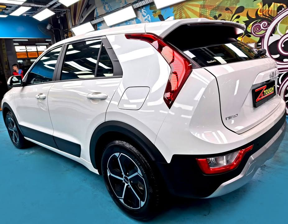 Rear three-quarter view of the white Kia Niro with its tall red tail light and alloy wheel.