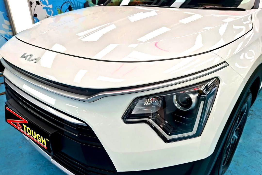 White bonnet and front bumper of the Kia Niro reflecting the workshop lights.