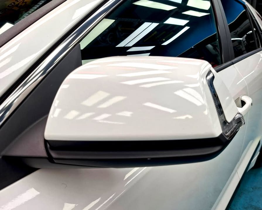 White side mirror cap reflecting the ceiling lights.