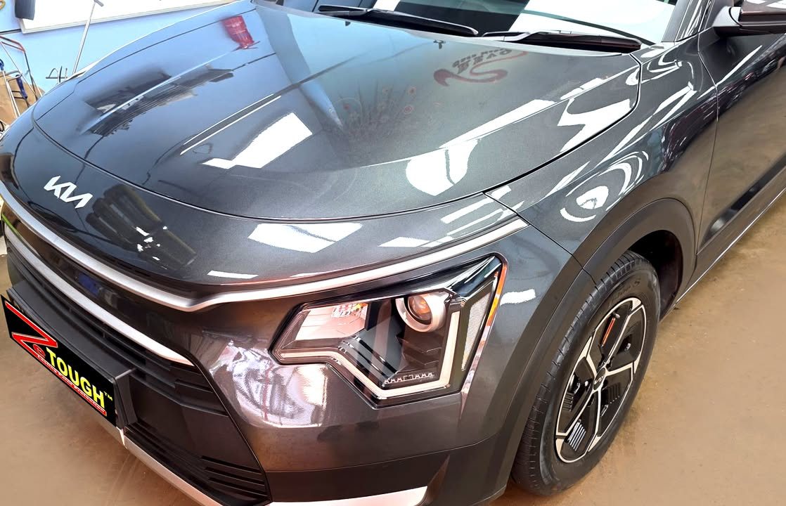 Front corner of the dark grey Niro showing the bonnet reflections and headlight.