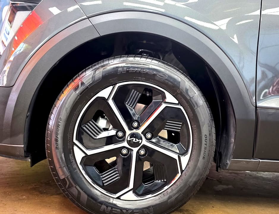 Two-tone alloy wheel with Kia centre cap under the black wheel arch trim.