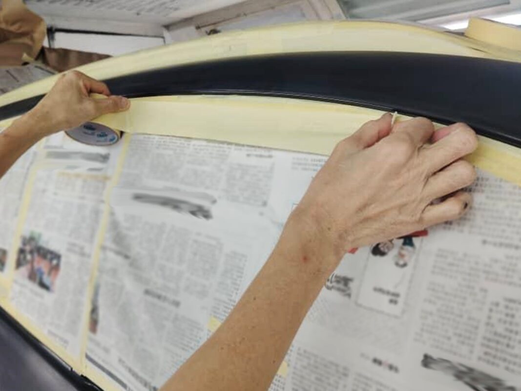 Masking the Kia Sorento's trim and glass before the spray booth.