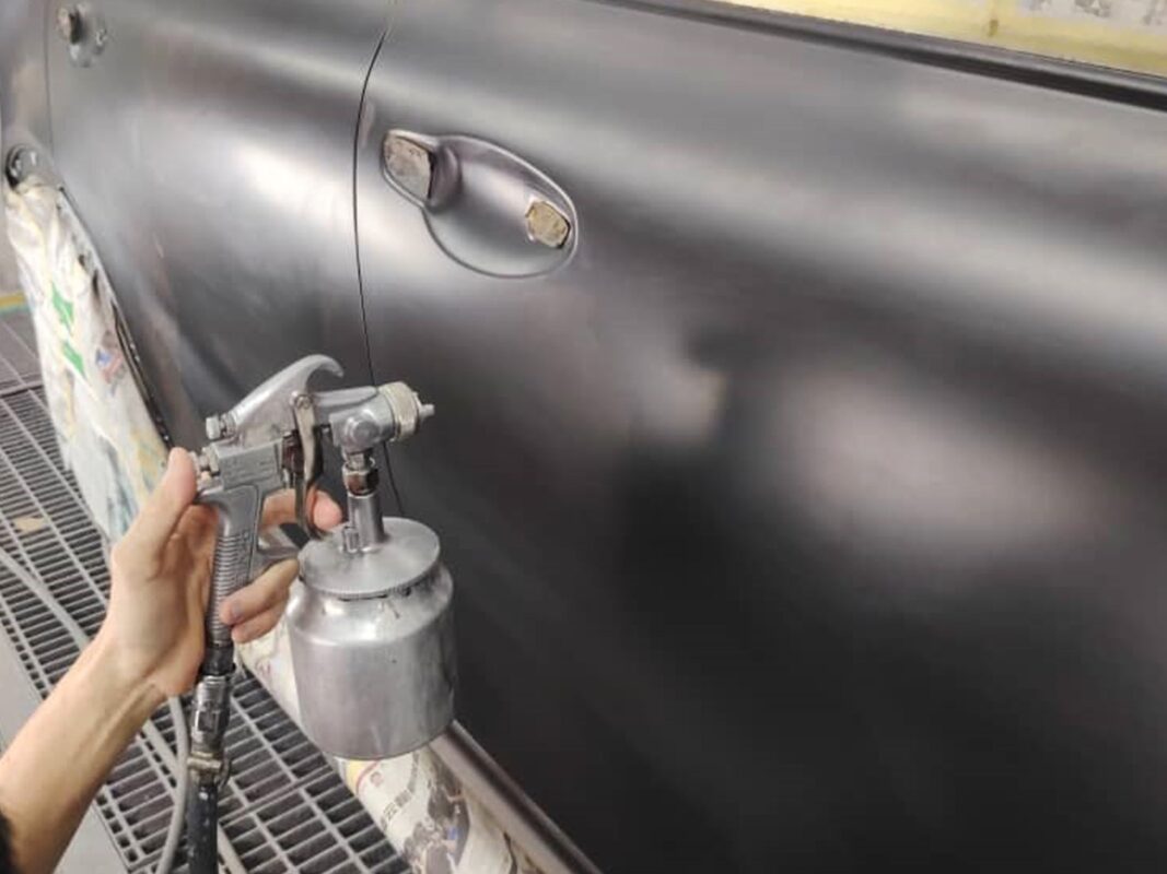 A Revol Carz painter laying the new coat onto a door of the Kia Sorento.