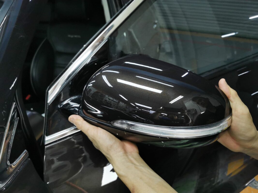 Refitting the painted wing mirror onto the Kia Sorento after spraying.