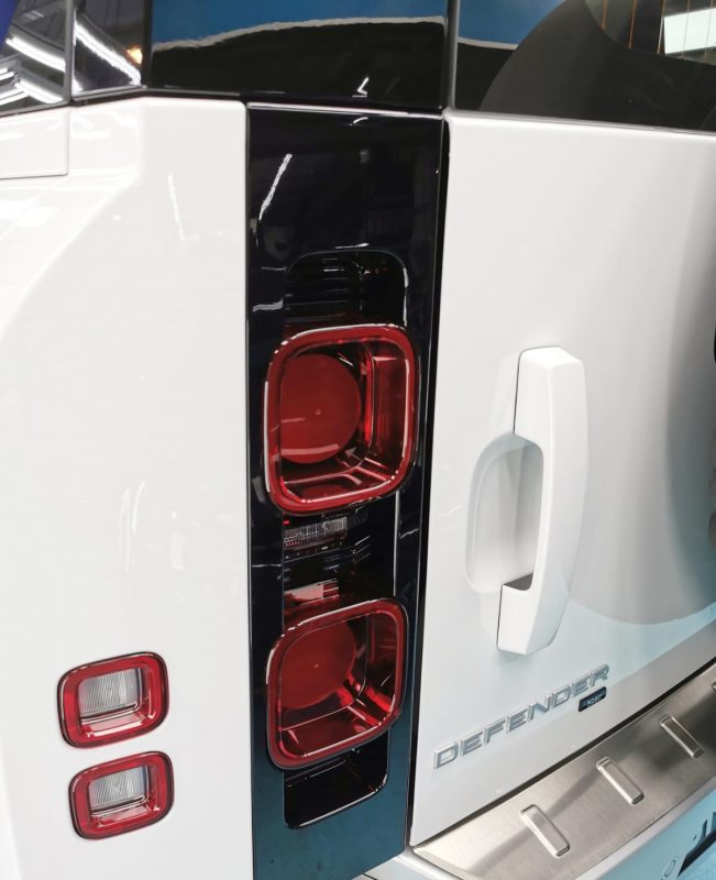 The coated bonnet of the Defender under workshop lighting.
