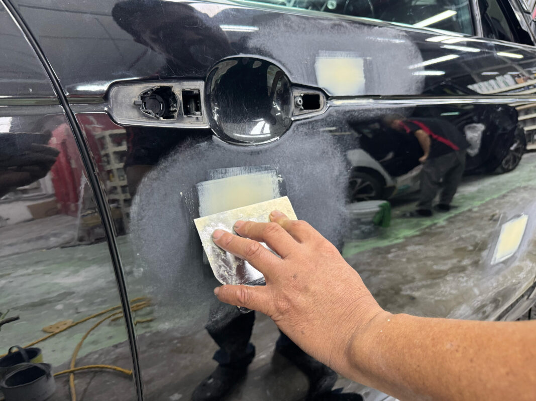 Body repair work underway on the Land Rover Discovery, filler applied to damaged areas.