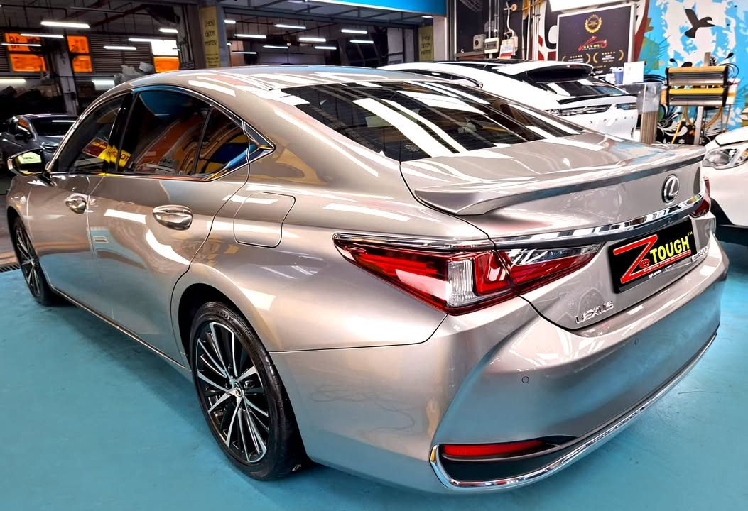 Rear three-quarter view of the champagne Lexus ES 300h in the workshop.