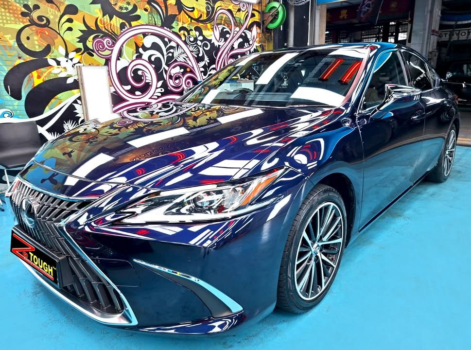 Front three-quarter view of the dark blue Lexus ES 300h in the workshop, lights reflected across the bonnet.