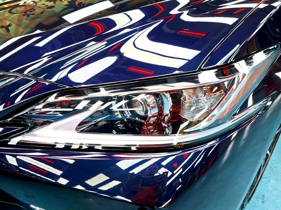 Close-up of the headlamp with light reflections on the dark blue bonnet.