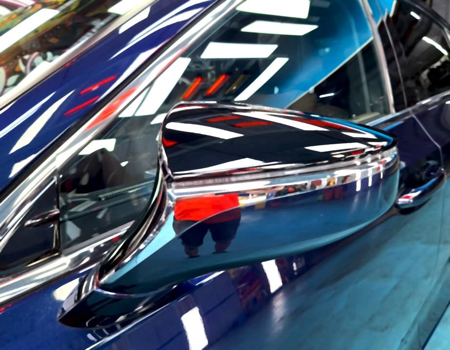 The dark blue wing mirror with chrome trim reflecting the workshop.