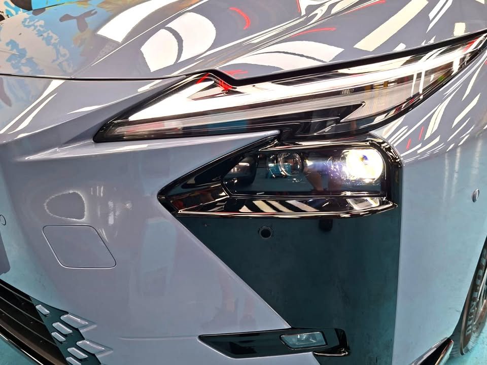 Close-up of the Lexus ES headlight and front bumper in blue grey paint.