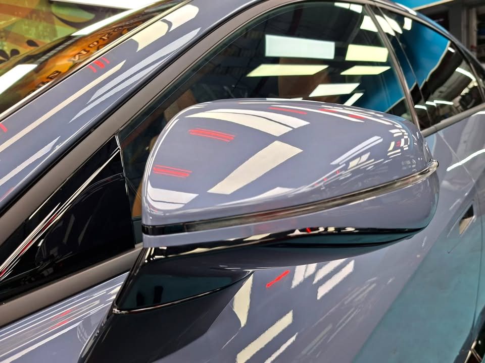 Blue grey wing mirror reflecting the workshop lights.