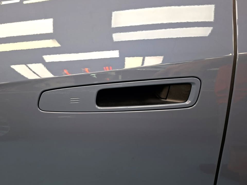 Flush door handle on the blue grey door panel.