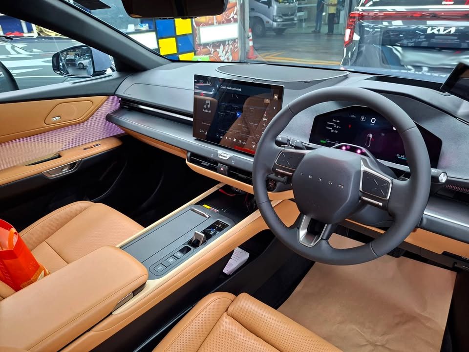 Lexus ES cabin with tan leather seats, steering wheel and wide dashboard screen.