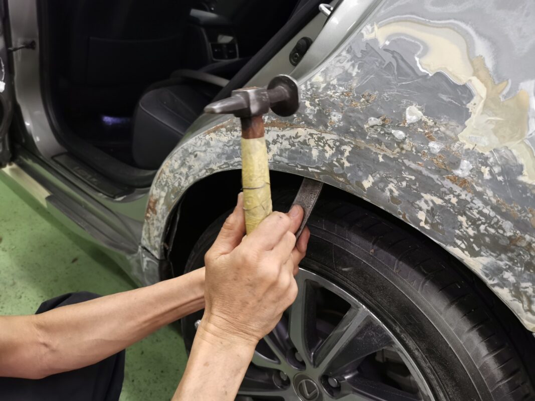 Inspecting the body surface and removing excess filler from a panel.