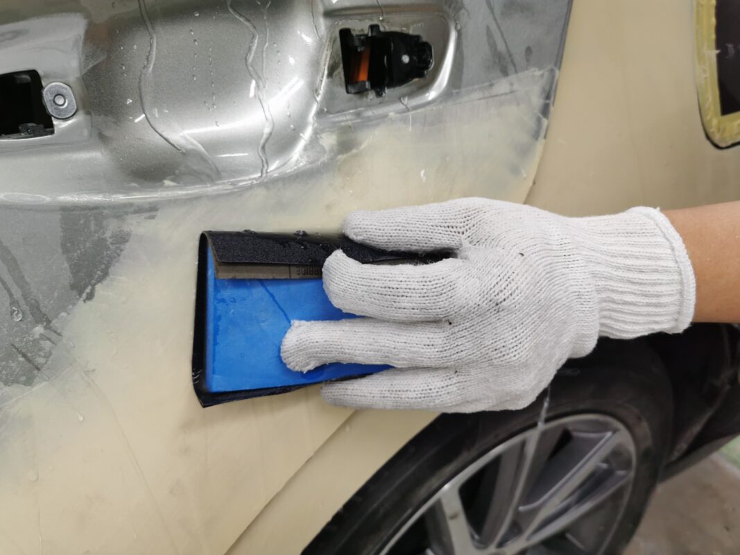 Wet-sanding the body of the Lexus ES300H to smooth the surface.
