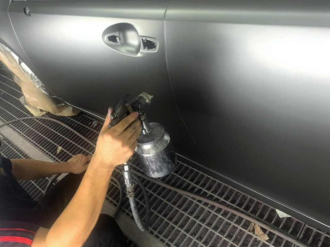 A Revol Carz painter applying fresh paint to the Lexus ES300h in the spray booth.
