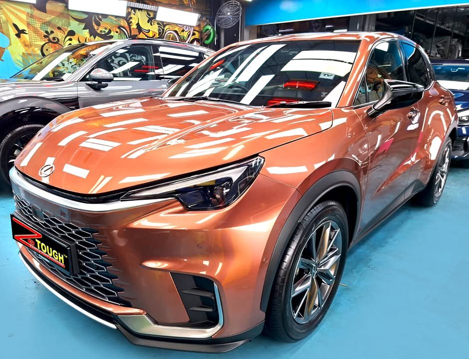 Copper Lexus LBX, front three-quarter view in the workshop with a ZeTough plate on the bumper.