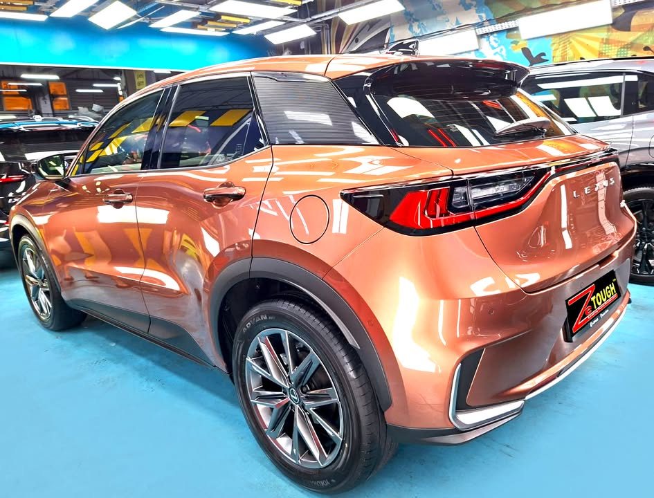 Rear three-quarter view of the copper Lexus LBX in the workshop.