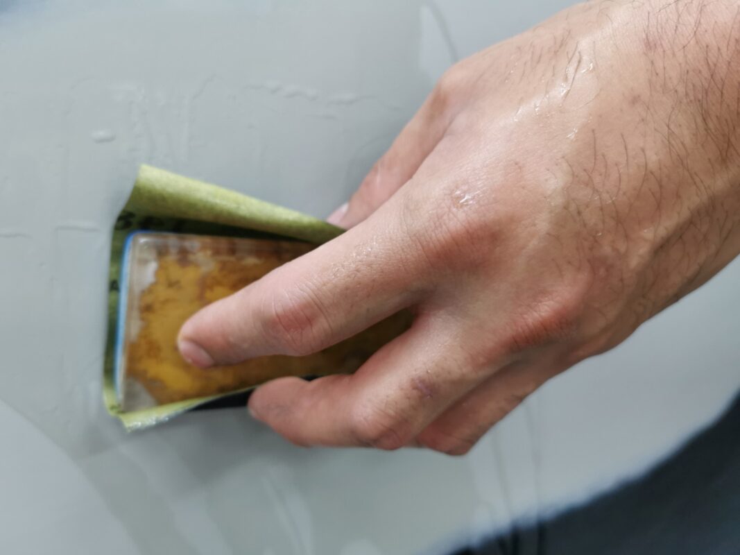 Wet-sanding the LS 460's panels to smooth the existing paintwork.