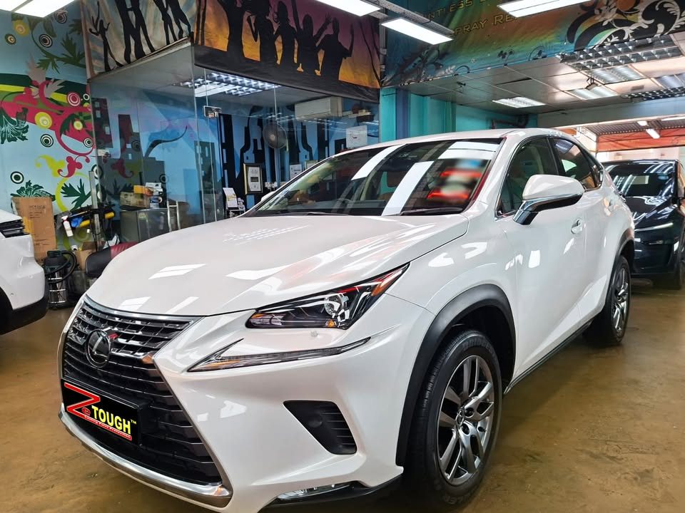 White Lexus NX200t from the front three-quarter in the Revol workshop, with a ZeTough plate on the grille.