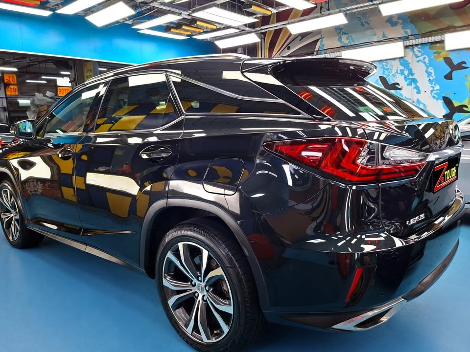 Rear three-quarter view of the black Lexus RX with tail lights and alloy wheel.