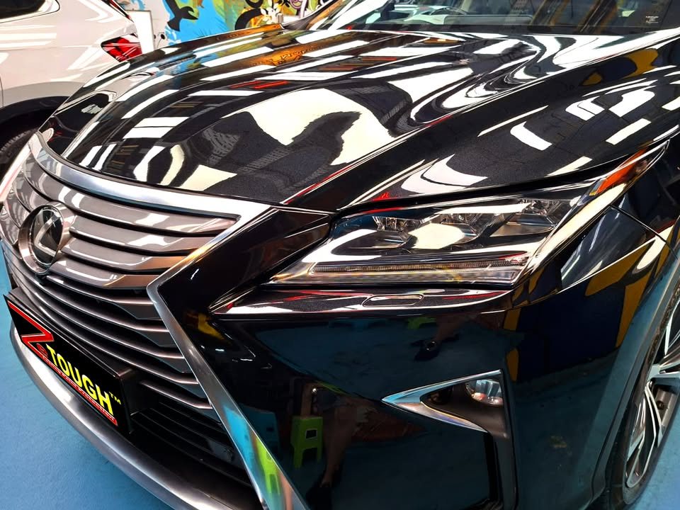 Close-up of the Lexus spindle grille and black bonnet reflecting the ceiling lights.