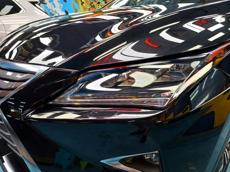 Close-up of the RX headlamp under the glossy black bonnet.