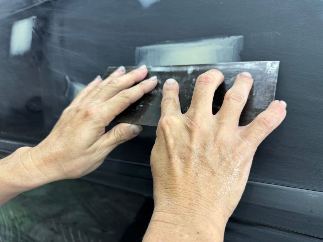 A technician examining the surface of the Lexus RX400h for paint imperfections.