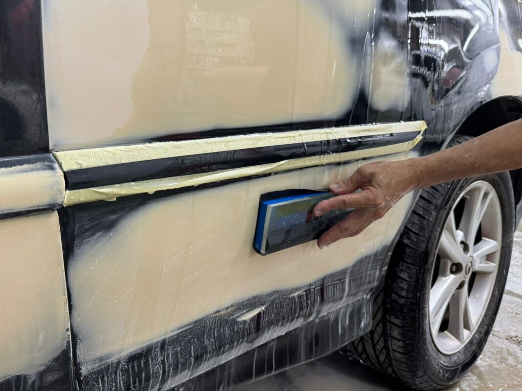 Wet-sanding a panel on the Lexus RX400h to level the surface.