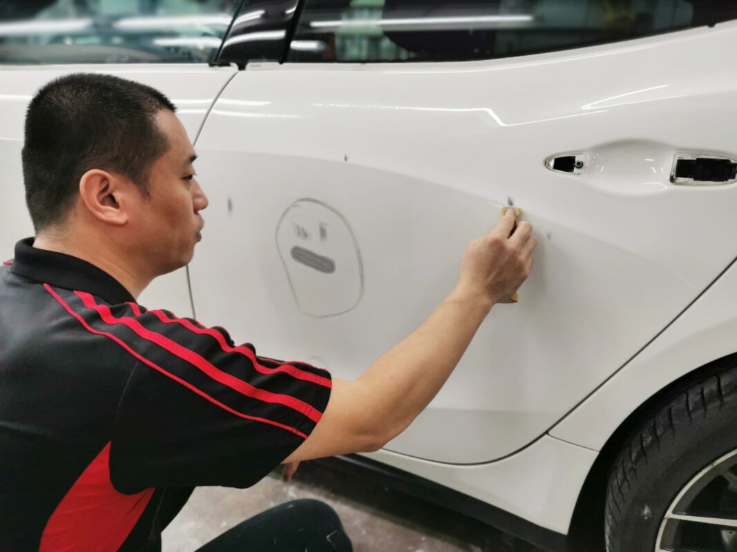 A Revol Carz specialist inspecting the Maserati Ghibli's surface for imperfections.