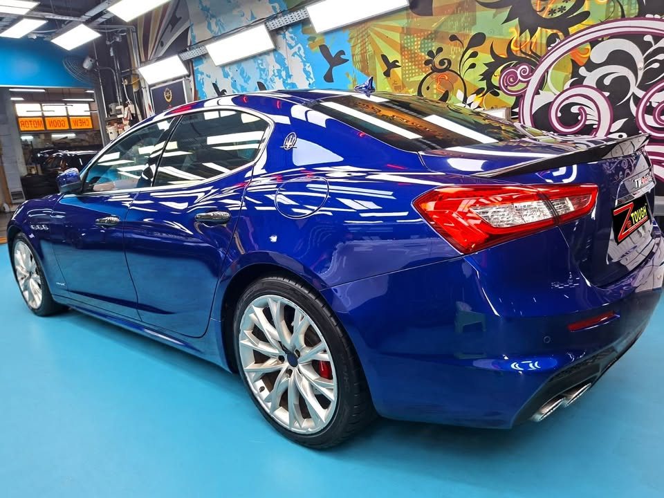 Rear three-quarter view of the blue Maserati Ghibli with silver alloy wheel and red tail lights.