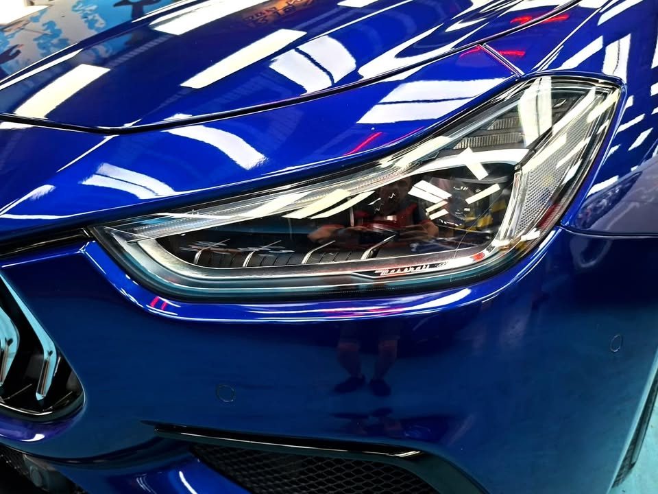 Close-up of the Ghibli headlamp beside the blue front wing.