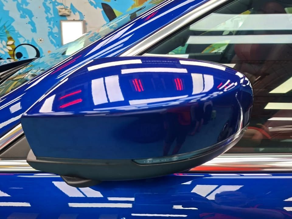 Blue side mirror cap with sharp reflections of the ceiling lights.