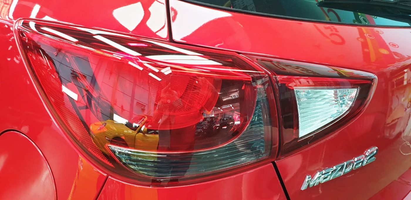 The coated bonnet of the Mazda 2 under workshop lighting.