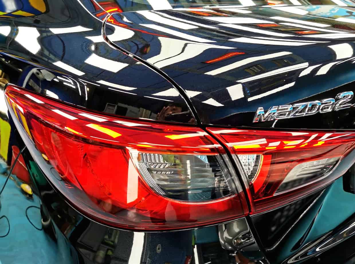The coated bonnet of the Mazda 2 under workshop lighting.