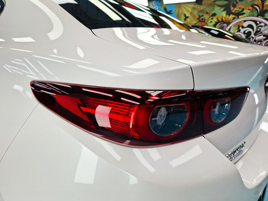The coated bonnet of the Mazda 3 under workshop lighting.