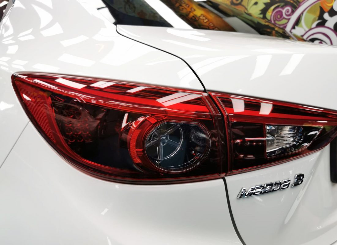 The coated bonnet of the Mazda 3 under workshop lighting.
