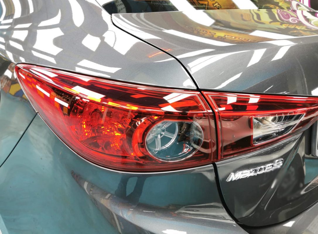 The coated bonnet of the Mazda 3 under workshop lighting.