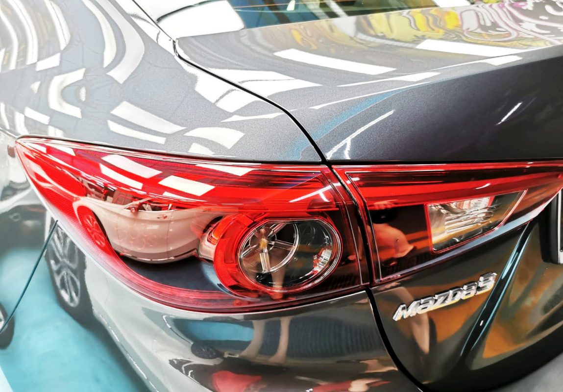 The coated bonnet of the Mazda 3 under workshop lighting.