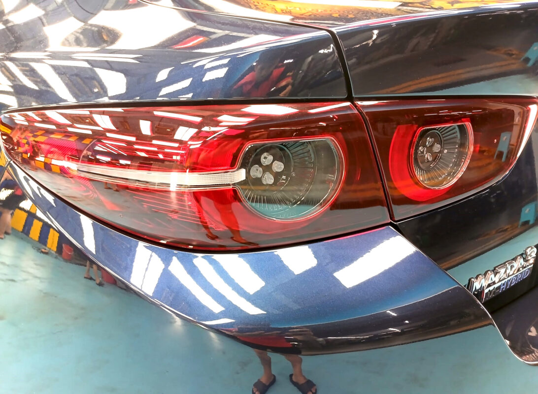 The coated bonnet of the Mazda 3 under workshop lighting.