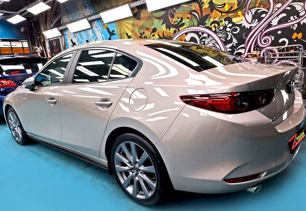 Rear three-quarter view of the silver Mazda 3 sedan with alloy wheel and tail lights.